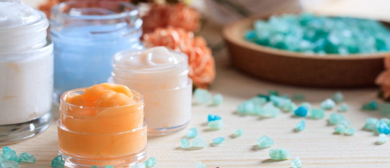 Get the best remedies for dry skin from Dr. Bonness. Lotions and scrubs against serene wooden backdrop.