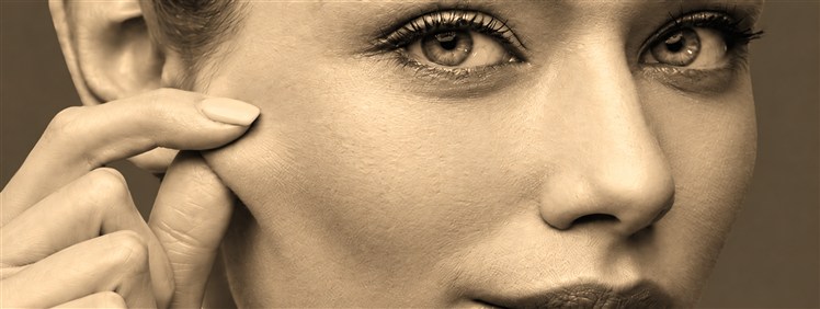Woman gently pressing a fingertip against her cheek