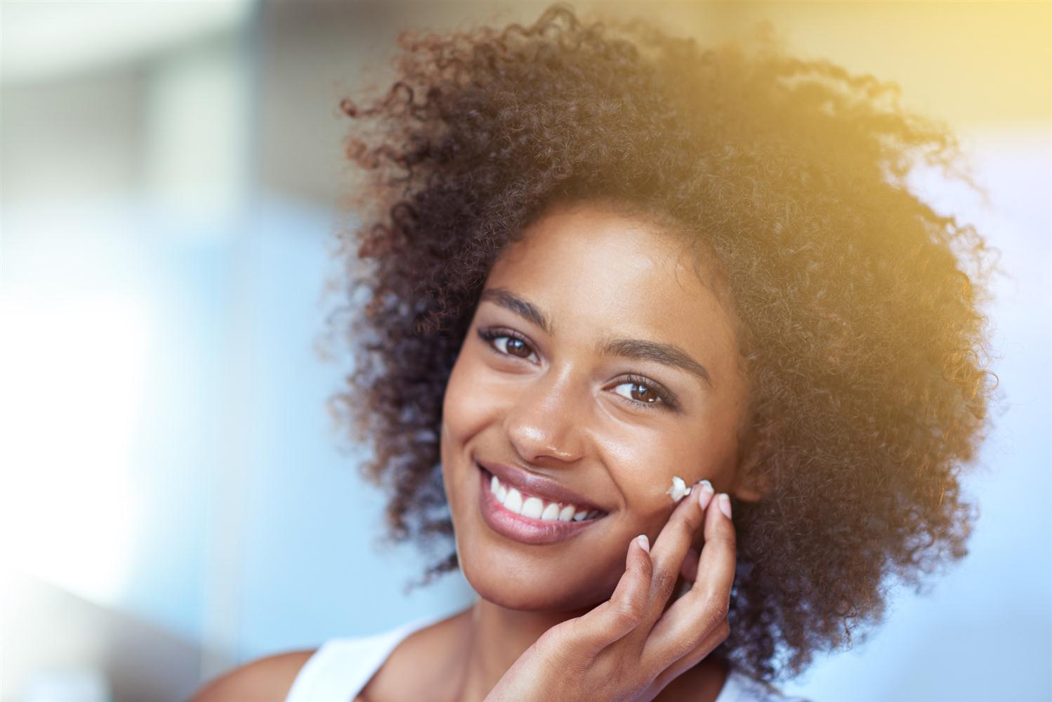 Woman applying skincare cream to her cheek
